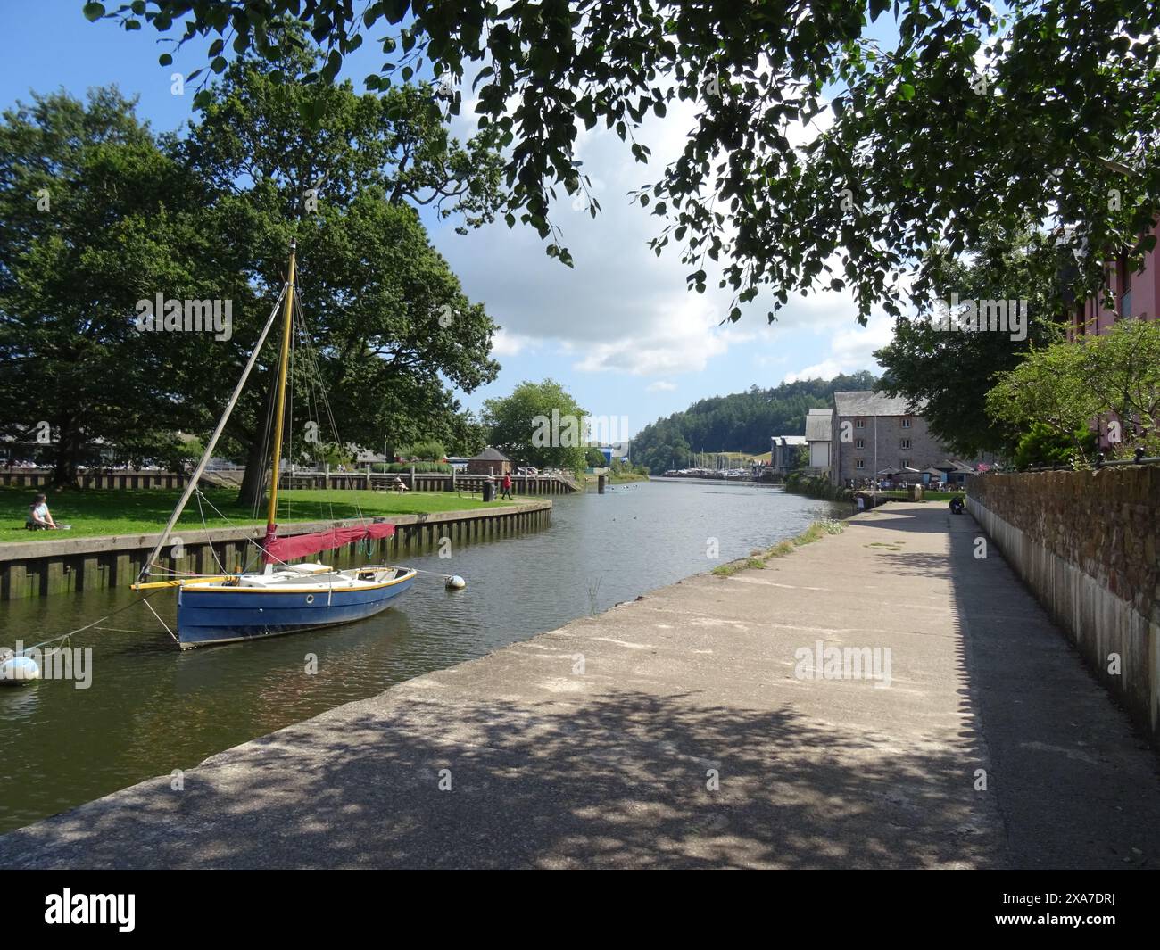 Ein Boot schwimmt in der Nähe von Gebäuden und Gras auf dem Wasser Stockfoto