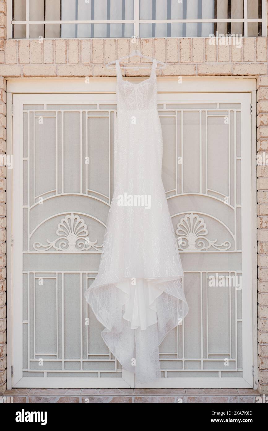 Ein Kleid, das an einem Kleiderbügel vor einer Tür hängt, an einer Wand Stockfoto