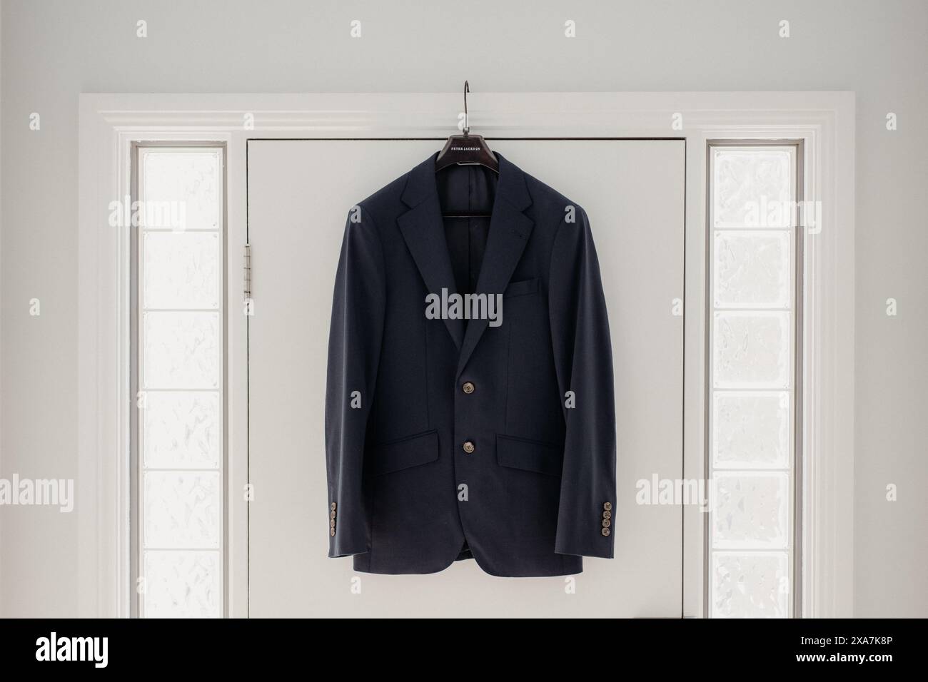 Ein blauer Anzug hängt an einer weißen Schlafzimmertür Stockfoto