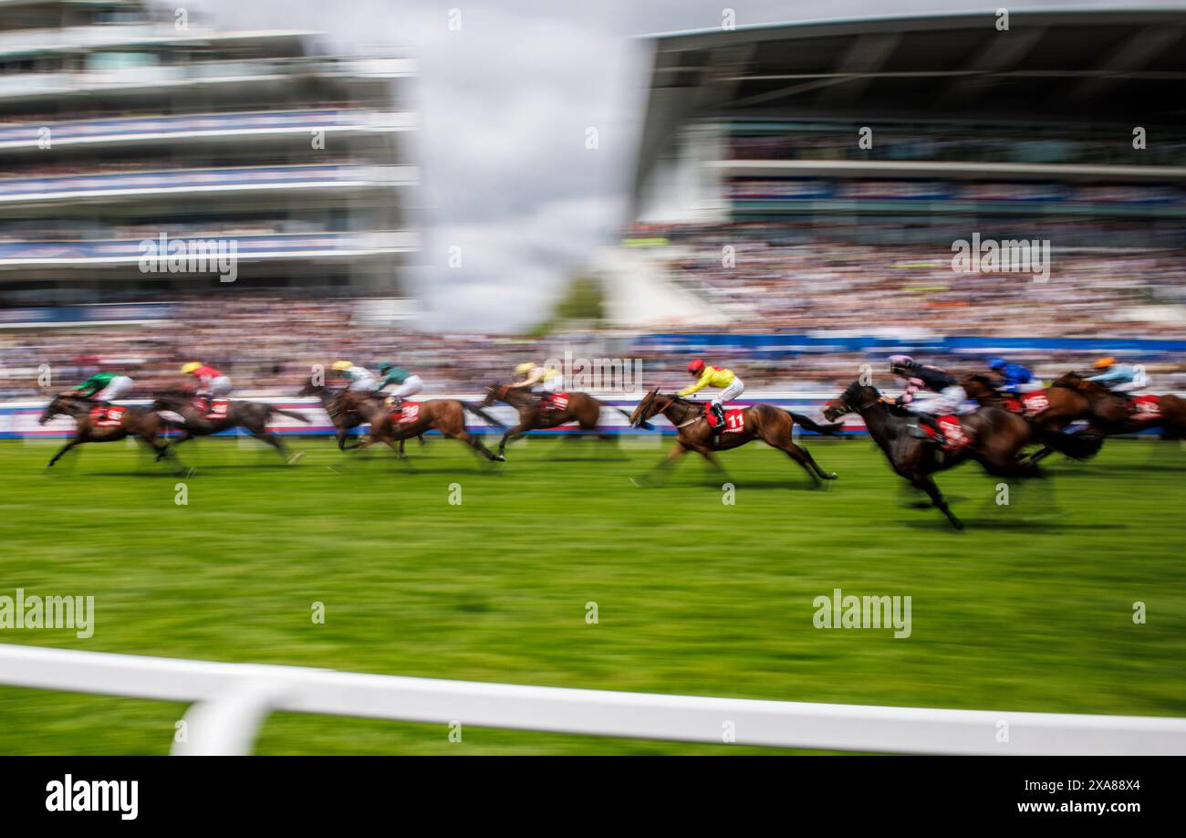 Pferde passieren die Haupttribüne beim Epsom Derby Festival. Das Derby ist eines der klassischen Pferderennen des Jahres. Stockfoto