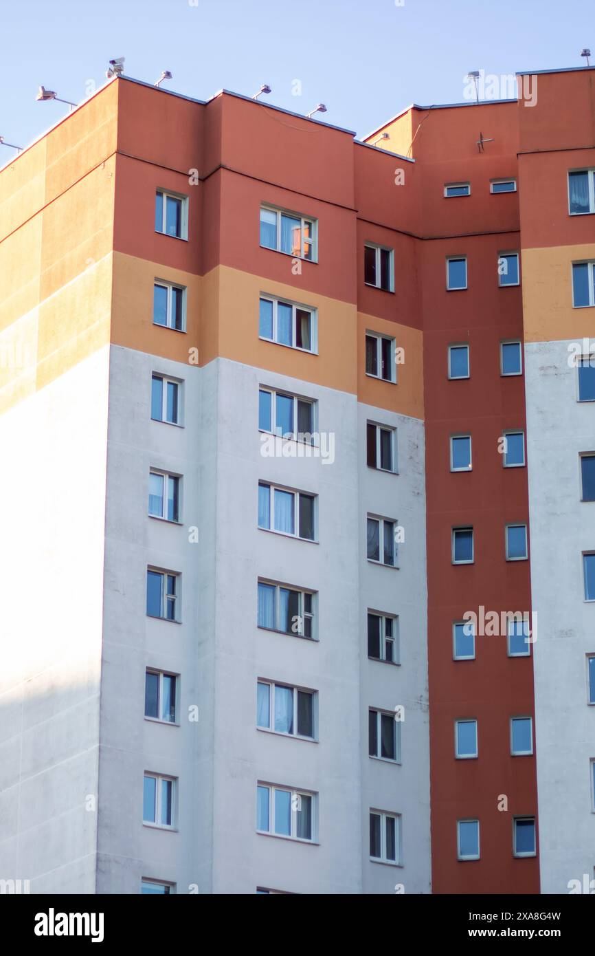 Vor dem Hintergrund eines blauen Himmels steht ein hoch aufragendes Gebäude mit urbanem Design und Verbundwerkstoff. Die Fassade der Wohnung spiegelt das A wider Stockfoto