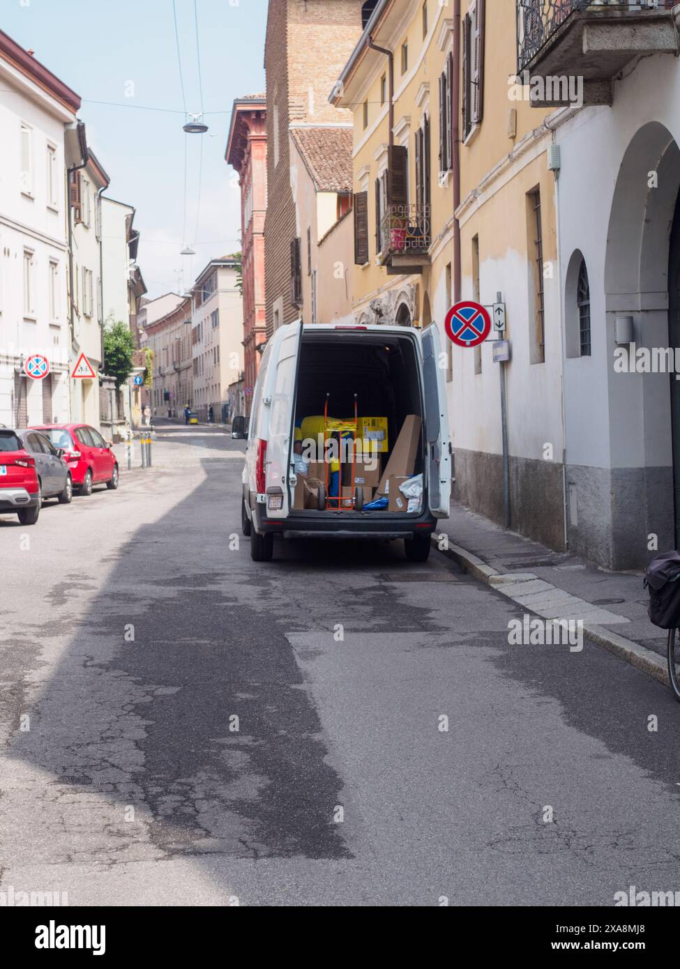Cremona, Italien - 27. Mai 2024 Weißer Lieferwagen wird entladen, mit Pappkartons und einem Handwagen, der hinten sichtbar ist. Der Van steht auf einem Narr Stockfoto