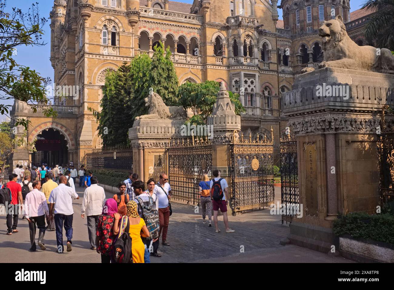 Passanten und westliche Touristen außerhalb des berühmten Chhatrapati Shivaji Maharaj Terminus aus der Kolonialzeit in Mumbai, Indien, das zum UNESCO-Weltkulturerbe gehört Stockfoto