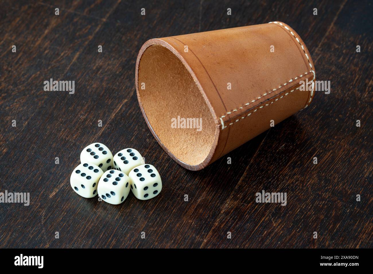 Leder Würfelbecher und Würfel auf dem Tisch, Rollen Sie alle Sechsen mit 5 Würfeln, die für Glücksspiel und Glück stehen Stockfoto