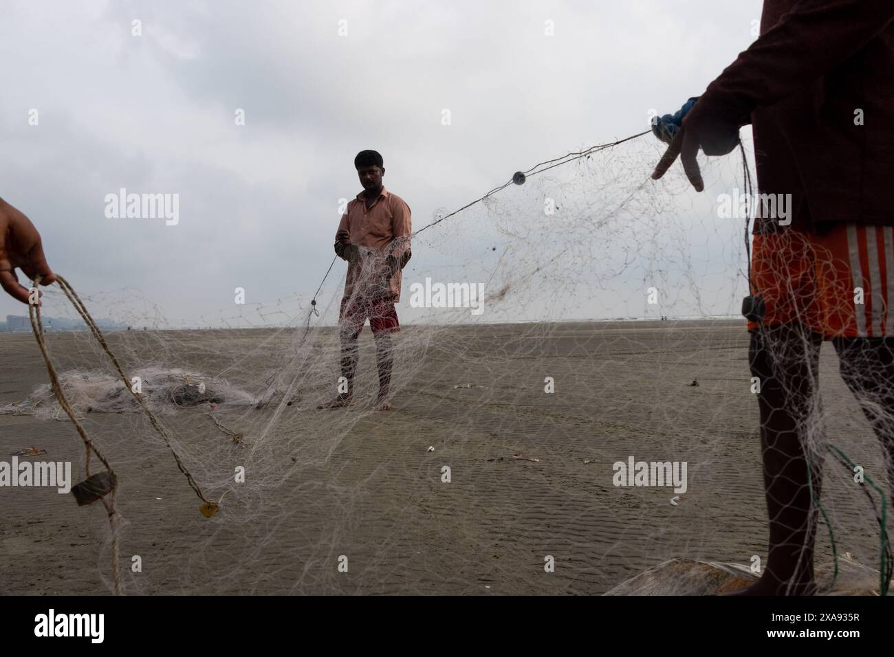 5. Juni 2024, Cox's Bazar, Chittagong, Bangladesch: Fischer, die Fischernetze für den Fischfang am Strand von Cox's Bazar in Bangladesch vorbereiten. Der Lebensunterhalt der Fischer hängt hier weitgehend von der Fischerei ab. Mit jedem Knoten und jeder Anpassung ehren sie eine zeitlose Tradition des Lebensunterhalts, die mit den Rhythmen der natürlichen Welt harmoniert. Cox's Bazar, der längste natürliche Meeresstrand der Welt, erstreckt sich über 120 km entlang der Südostküste Bangladeschs. Berühmt für seinen goldenen Sand, die pulsierenden Sonnenuntergänge und die sanfte Brandung, zieht es jährlich Millionen von Touristen an. (Bild: © Joy Stockfoto