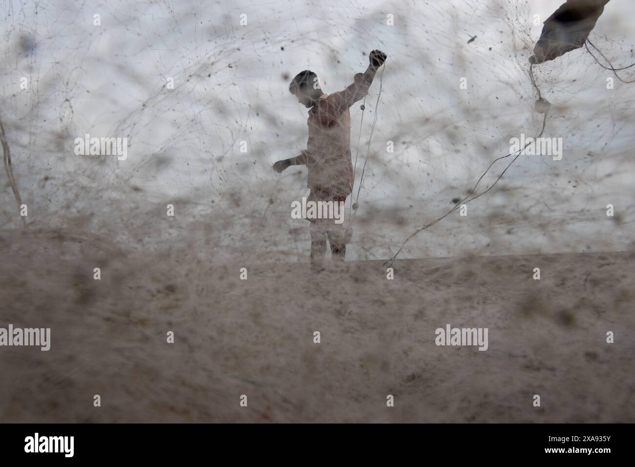 5. Juni 2024, Cox's Bazar, Chittagong, Bangladesch: Fischer, die Fischernetze für den Fischfang am Strand von Cox's Bazar in Bangladesch vorbereiten. Der Lebensunterhalt der Fischer hängt hier weitgehend von der Fischerei ab. Mit jedem Knoten und jeder Anpassung ehren sie eine zeitlose Tradition des Lebensunterhalts, die mit den Rhythmen der natürlichen Welt harmoniert. Cox's Bazar, der längste natürliche Meeresstrand der Welt, erstreckt sich über 120 km entlang der Südostküste Bangladeschs. Berühmt für seinen goldenen Sand, die pulsierenden Sonnenuntergänge und die sanfte Brandung, zieht es jährlich Millionen von Touristen an. (Bild: © Joy Stockfoto