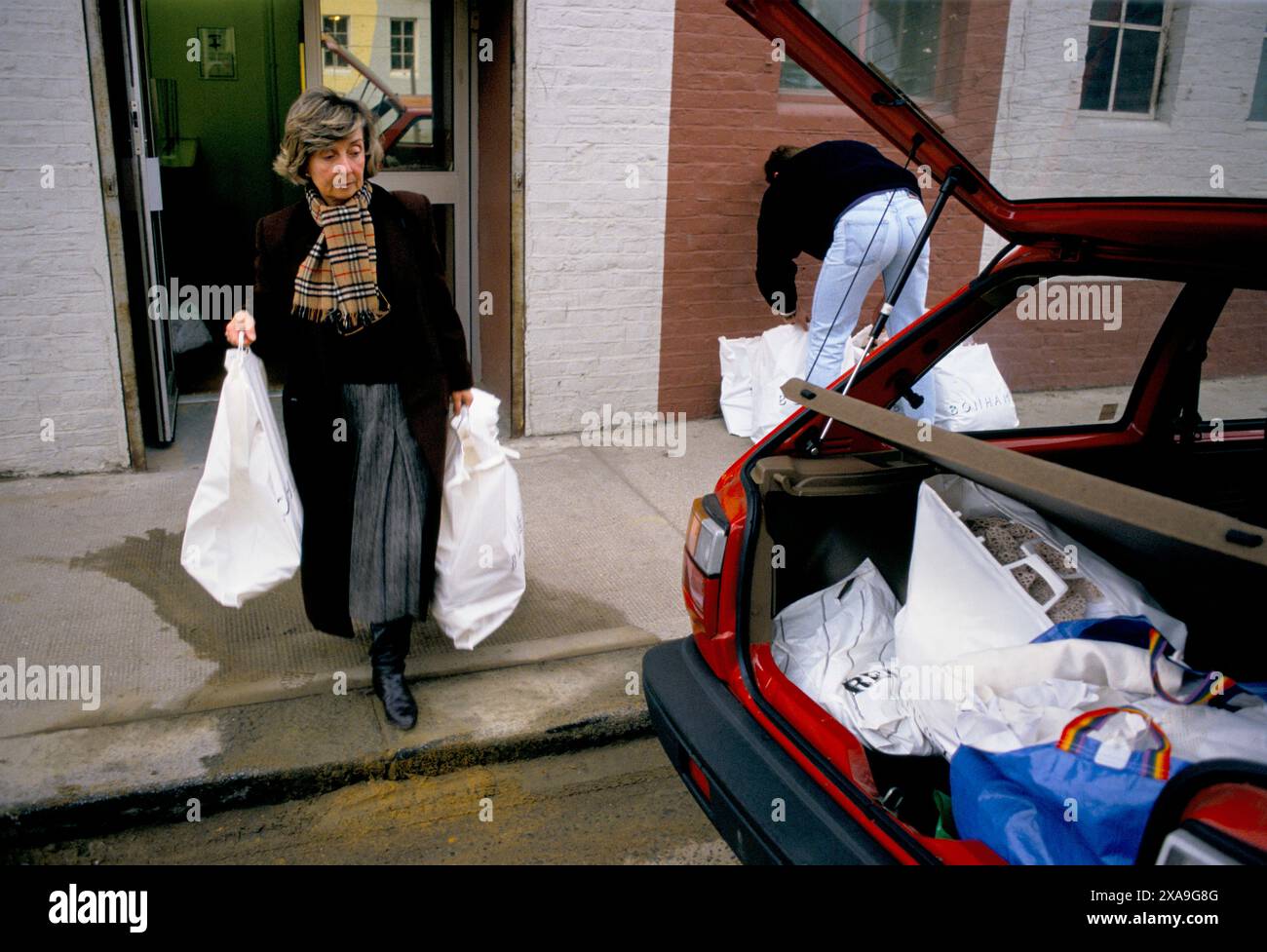 Händler aus Spanien kaufen Vintage-Kleidung im Bonhams Auktionshaus in Lots Road, Fulham London. (Das billige Ende des Marktes) Sie und ihr Partner gaben £1.500,00 für Einkäufe aus und verfrachten sie in das Auto, um sie mit Gewinn zurückzuholen und zu verkaufen. HOMER SYKES AUS DEN 1990ER JAHREN Stockfoto