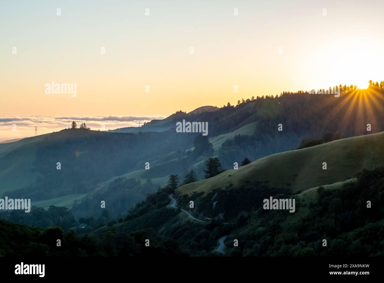 Ein Sonnenuntergang auf dem Skyline Blvd in Woodside, CA, mit Sonne auf den Hügeln und Meeresschicht, die die Küste im Hintergrund bedeckt Stockfoto