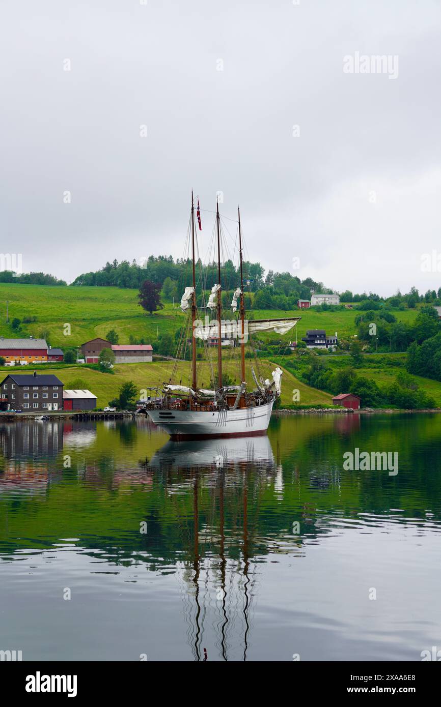 Ein weißes Schiff segelt in der Nähe von Hügelhäusern auf dem Wasser Stockfoto