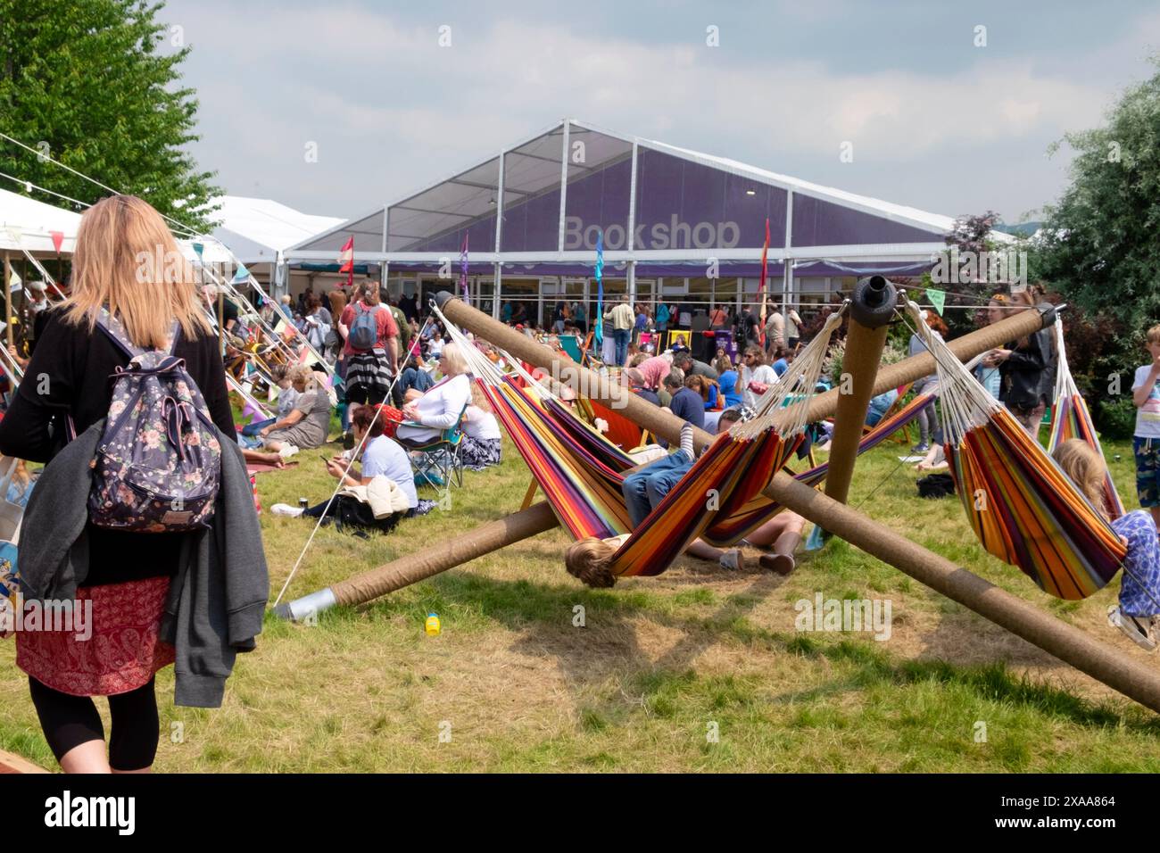 Kinder spielen auf Hängematten Menschen im Garten entspannen sich außerhalb des Buchladens Hay Literary Festival Hay-on-Wye Wales Großbritannien 2024 Großbritannien KATHY DEWITT Stockfoto