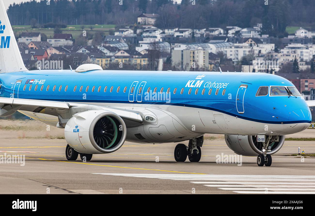 Ein Embraer 195-E2 vom KLM Cityhopper fährt mit dem Taxi auf die Start- und Landebahn am Flughafen Zürich, wo sie auf die Freigabe wartet. Registrierung PH-NXO. (Zu Stockfoto
