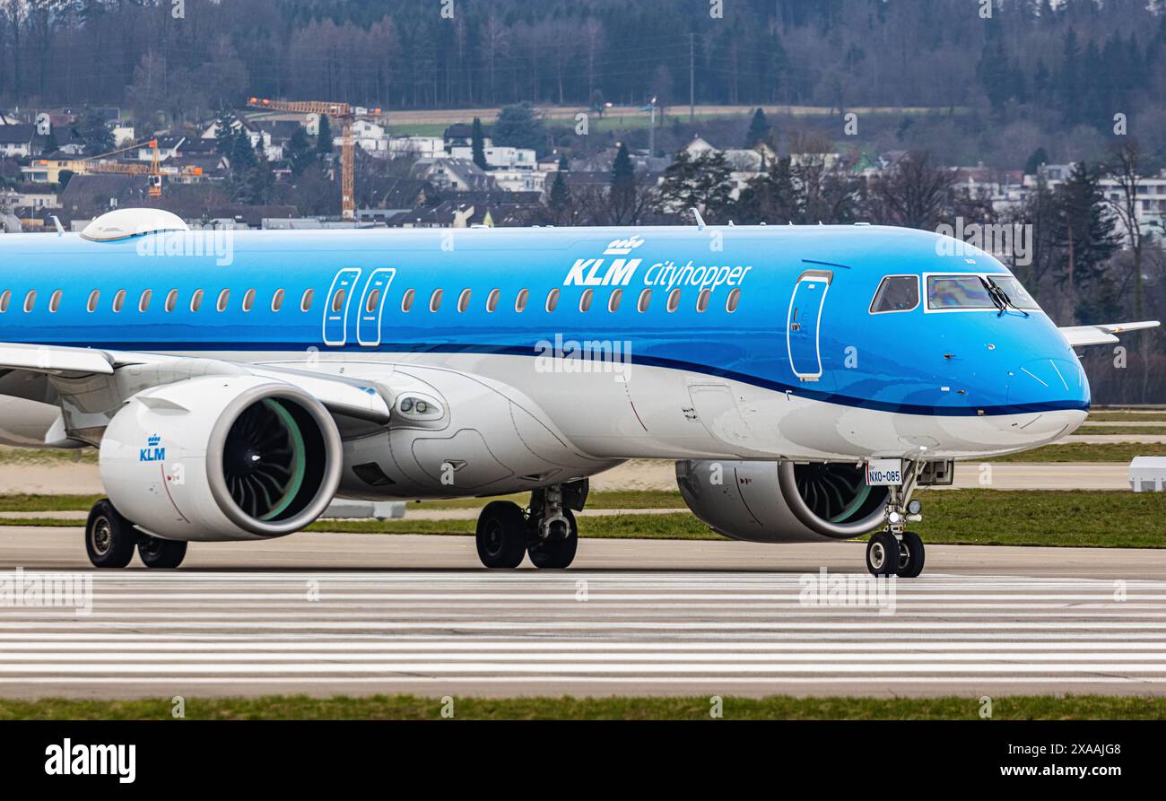 Ein Embraer 195-E2 vom KLM Cityhopper fährt mit dem Taxi auf die Start- und Landebahn am Flughafen Zürich, wo sie auf die Freigabe wartet. Registrierung PH-NXO. (Zu Stockfoto