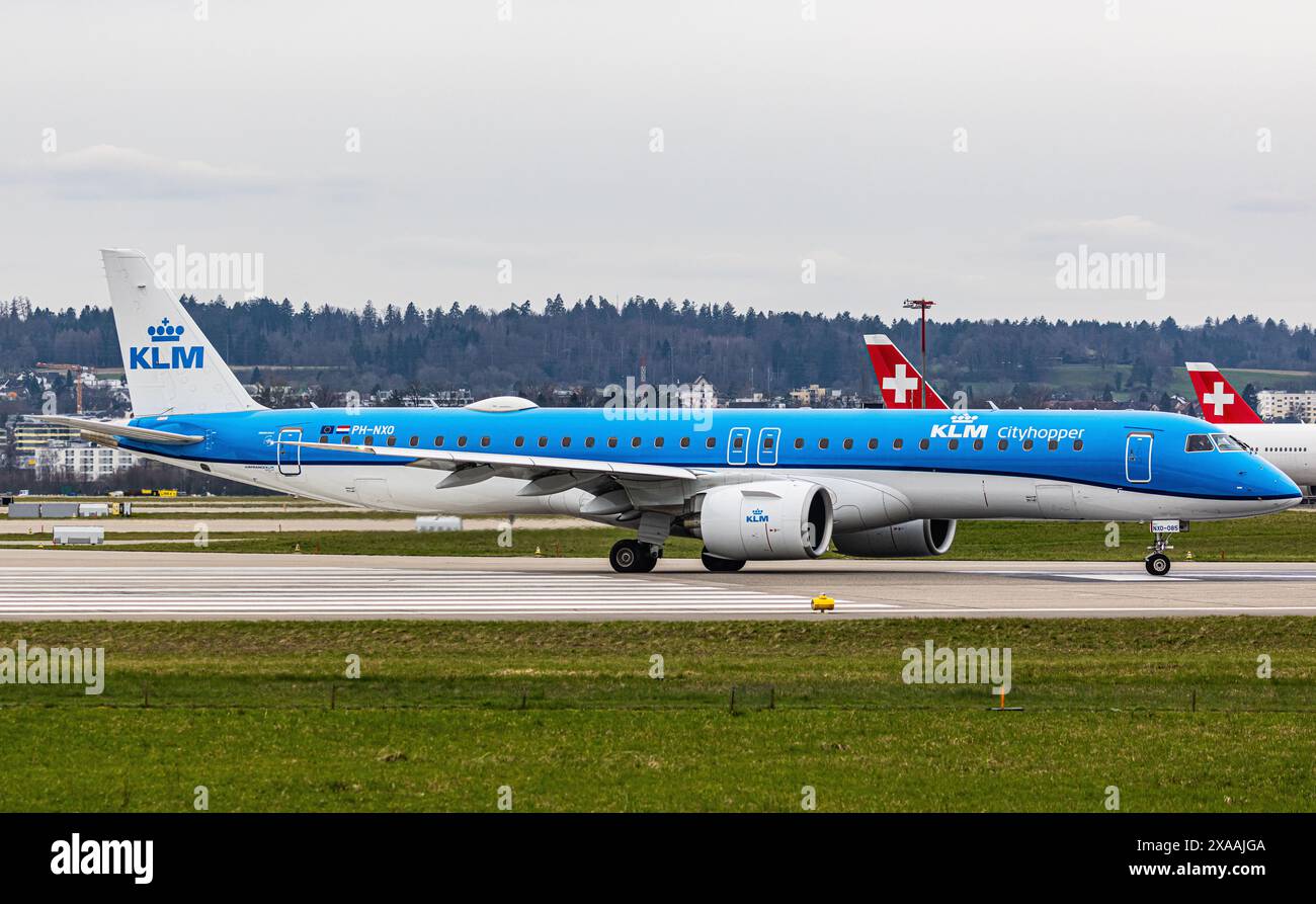 Ein Embraer 195-E2 vom KLM Cityhopper fährt mit dem Taxi auf die Start- und Landebahn am Flughafen Zürich, wo sie auf die Freigabe wartet. Registrierung PH-NXO. (Zu Stockfoto