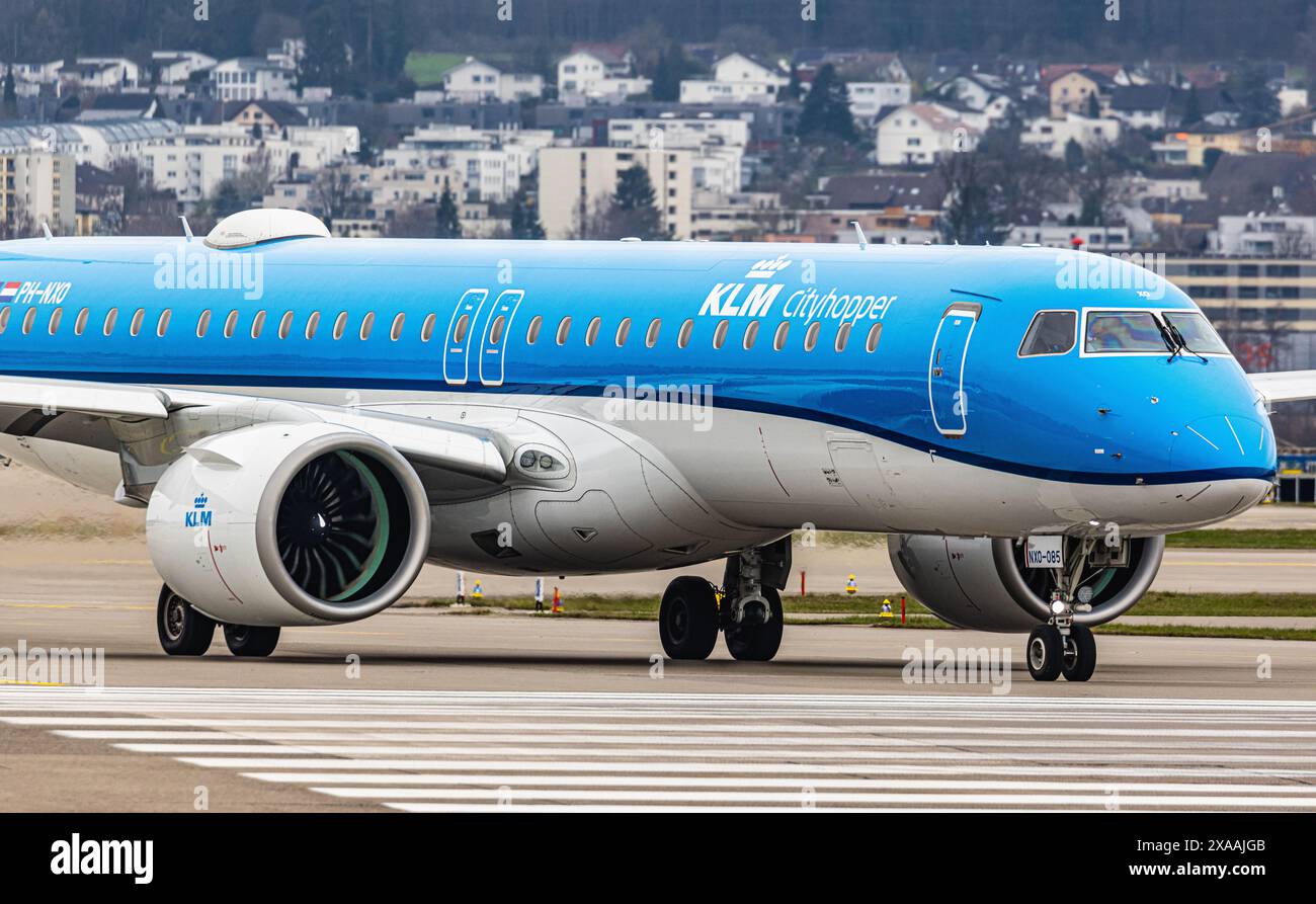 Ein Embraer 195-E2 vom KLM Cityhopper fährt mit dem Taxi auf die Start- und Landebahn am Flughafen Zürich, wo sie auf die Freigabe wartet. Registrierung PH-NXO. (Zu Stockfoto