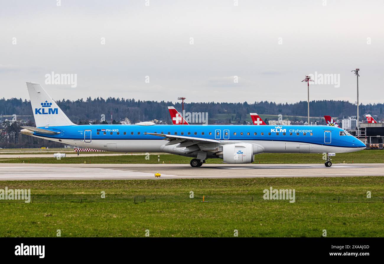 Ein Embraer 195-E2 vom KLM Cityhopper fährt mit dem Taxi auf die Start- und Landebahn am Flughafen Zürich, wo sie auf die Freigabe wartet. Registrierung PH-NXO. (Zu Stockfoto