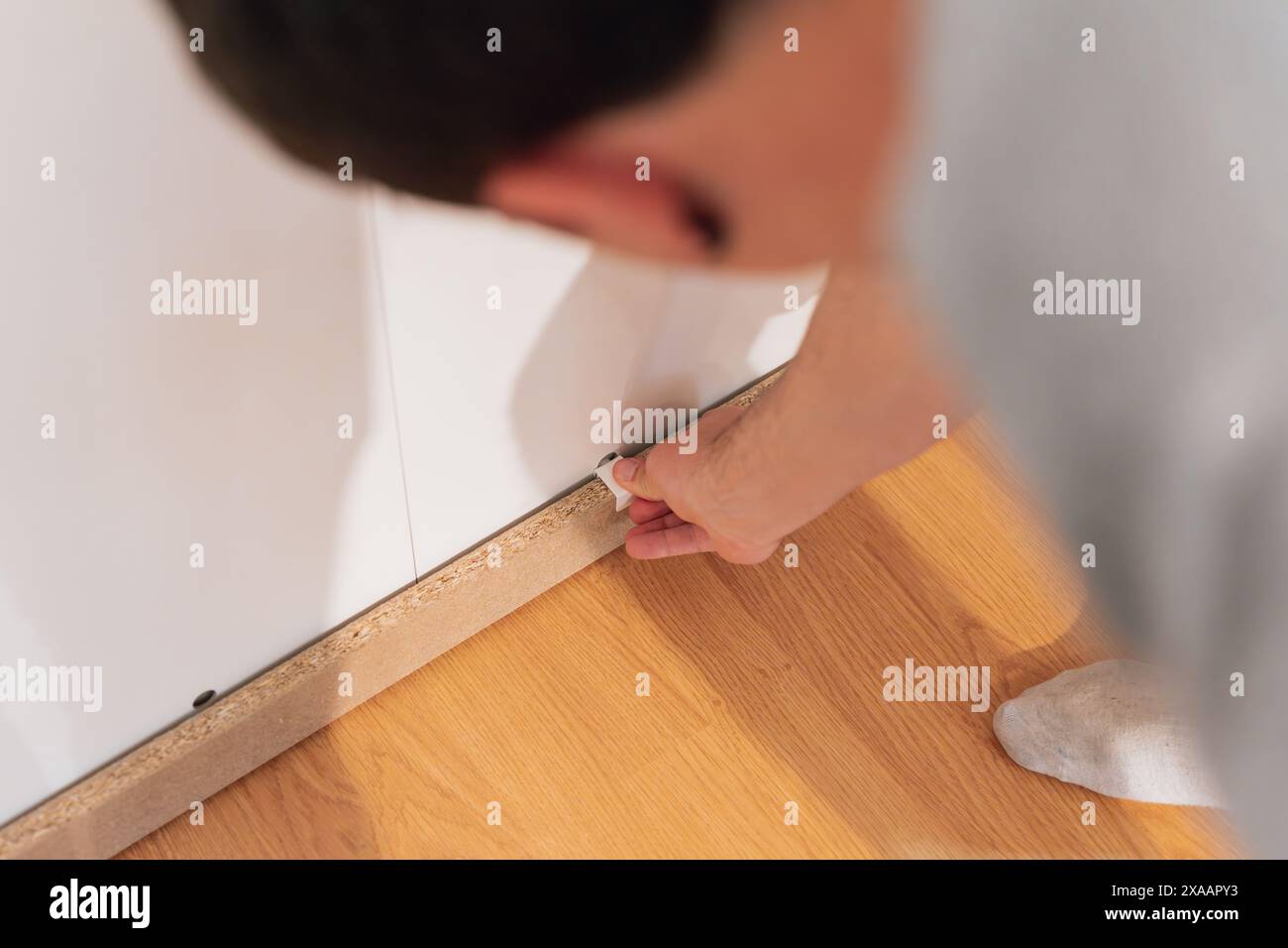 Ein junger Mann, der Teile eines neuen Kleiderschranks in sein Haus stellt. Möbelkonzept Stockfoto