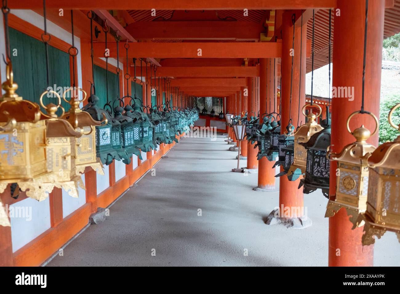 Zwei Reihen von Windlichtern in leuchtenden goldenen und grünen Farben hängen anmutig von einem Portikus eines Tempels in Nara, Honshu, Japan, Asien Stockfoto