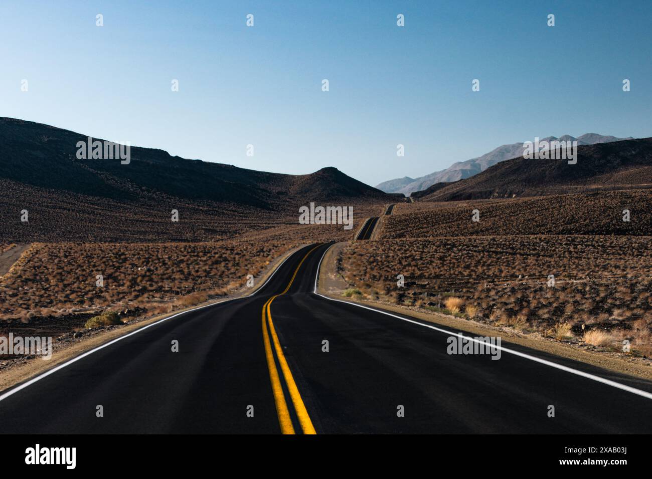 Einsamer, hügeliger Highway in der Wüste von Death Valley, Kalifornien, USA, Nordamerika Stockfoto