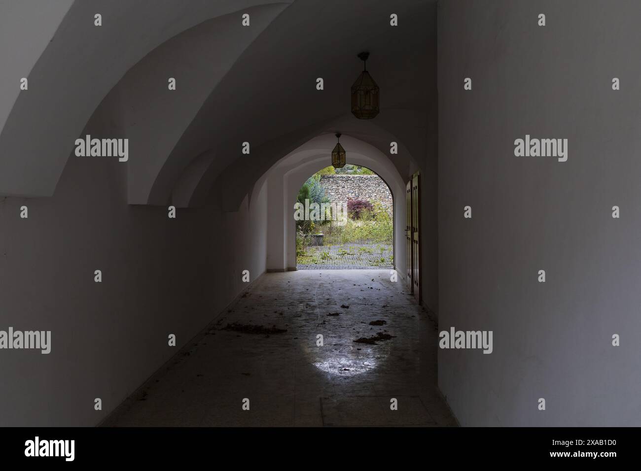 Fotografie eines dunklen Tunnelbogens in einem mittelalterlichen Haus mit offenem Tor am Ende Stockfoto
