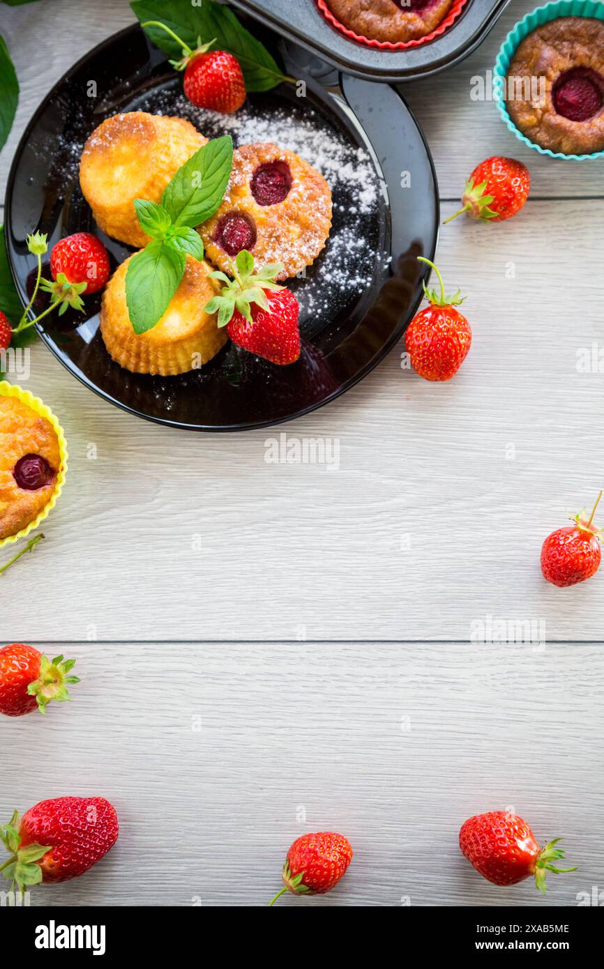 Süße Quark-Muffins mit Erdbeerfüllung, auf einem Teller auf einem Holztisch. Stockfoto
