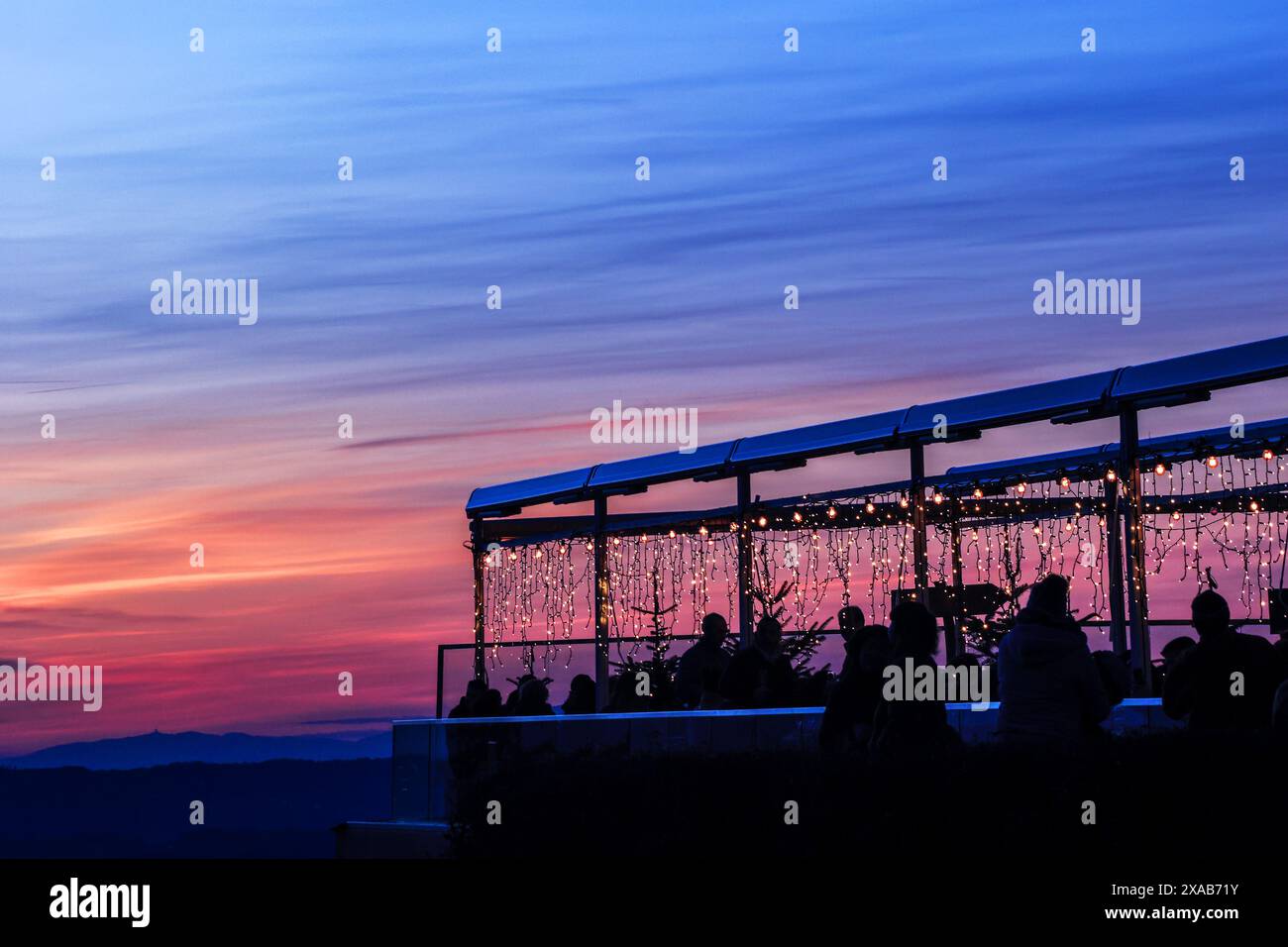 Die Leute im gut beleuchteten Restaurant auf dem Uetliberg genießen den abendlichen Sonnenuntergang, um das neue Jahr zu feiern, Zürich Schweiz Stockfoto