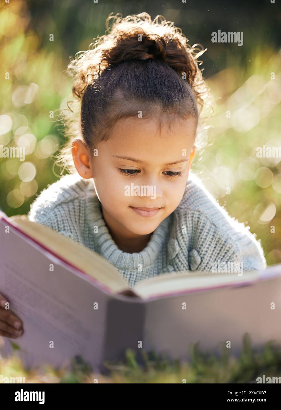 Kinder, Bildung und Mädchen in einem Garten mit Buch zum Lesen, Entspannen und zur Entwicklung der Kinder in der Natur. Frieden, Fantasie oder ruhiges Kind mit Märchen Stockfoto