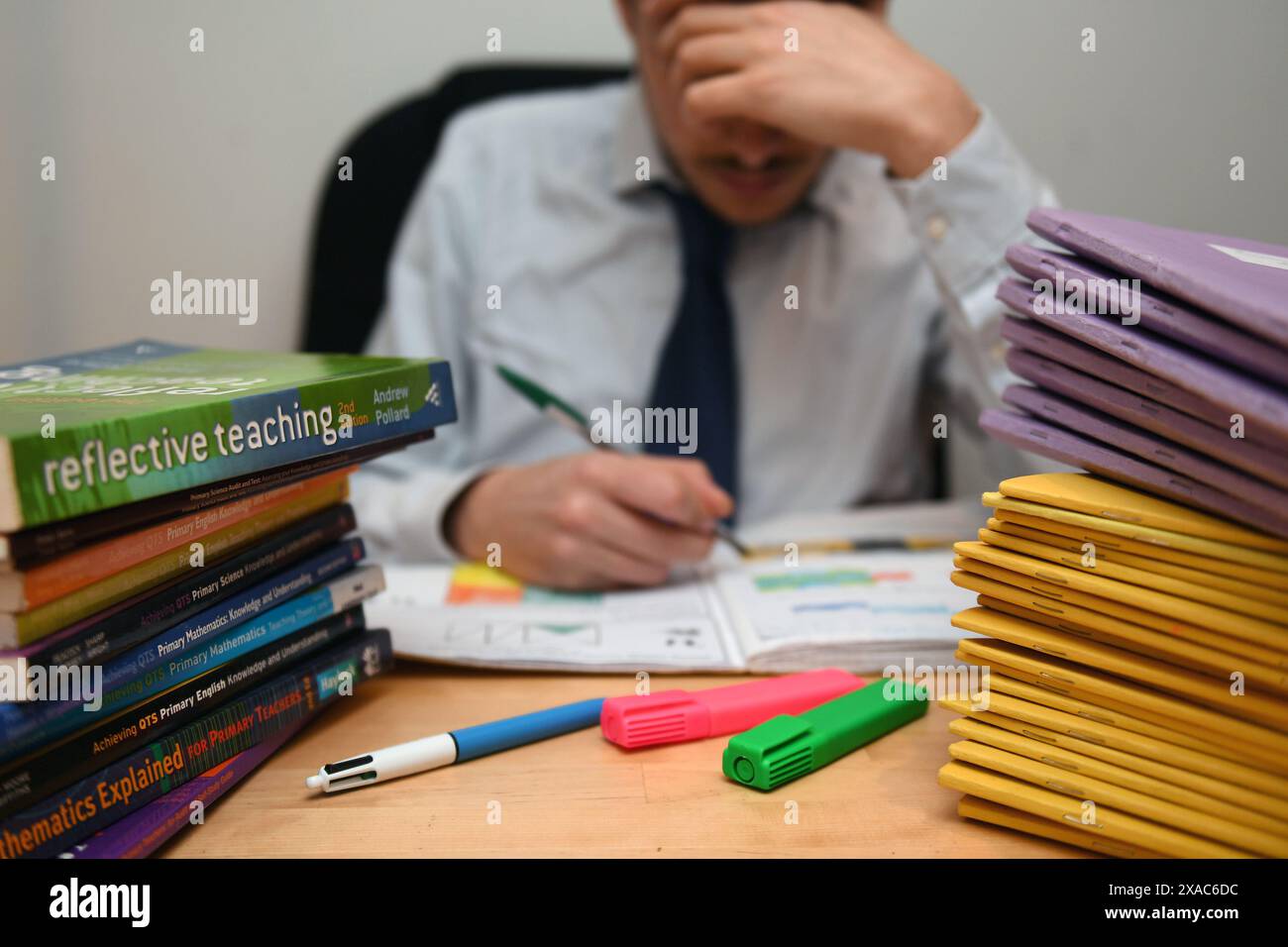 Aktenfoto vom 03/17 eines Schullehrers, der neben einem Stapel von Klassenbüchern gestresst aussieht. Die Lehrkräfte arbeiten durchschnittlich mehr als 11 Stunden pro Woche, um ihre immer komplexer werdenden Aufgaben in Angriff zu nehmen, haben Forschungsergebnisse vorgeschlagen. Schottlands größte lehrgewerkschaft das Educational Institute of Scotland (Eis) hat die Minister aufgefordert, das Problem der übermäßigen Arbeitsbelastung angesichts der Sorge um die Gesundheit und das Wohlergehen der Lehrer ernst zu nehmen. Ausgabedatum: Donnerstag, 6. Juni 2024. Stockfoto