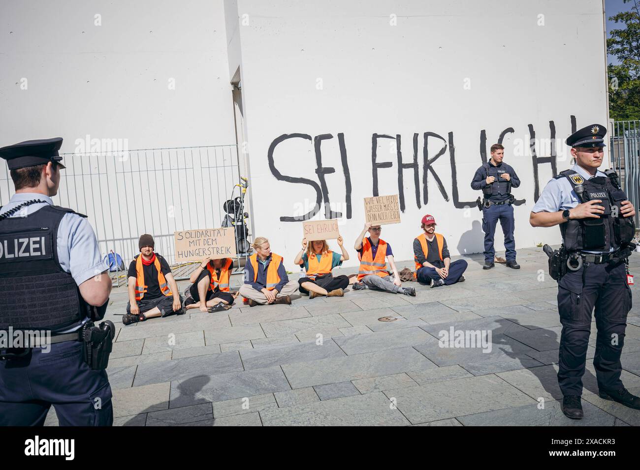 Demonstranten sitzen mit Schildern vor dem Bundeskanzleramt, die Demonstrierenden haben mit Schwarzer Farbe sei ERHRLICH an die Fassade vom Bundeskanzleramt geschrieben in Berlin, 06.06.2024. Berlin Deutschland *** Demonstranten sitzen mit Schildern vor dem Bundeskanzleramt, die Demonstranten haben mit schwarzer Farbe sei ERHRLICH auf die Fassade des Bundeskanzleramtes in Berlin geschrieben, 06 06 2024 Berlin Deutschland Copyright: xFelixxZahnxphotothek.dex Stockfoto