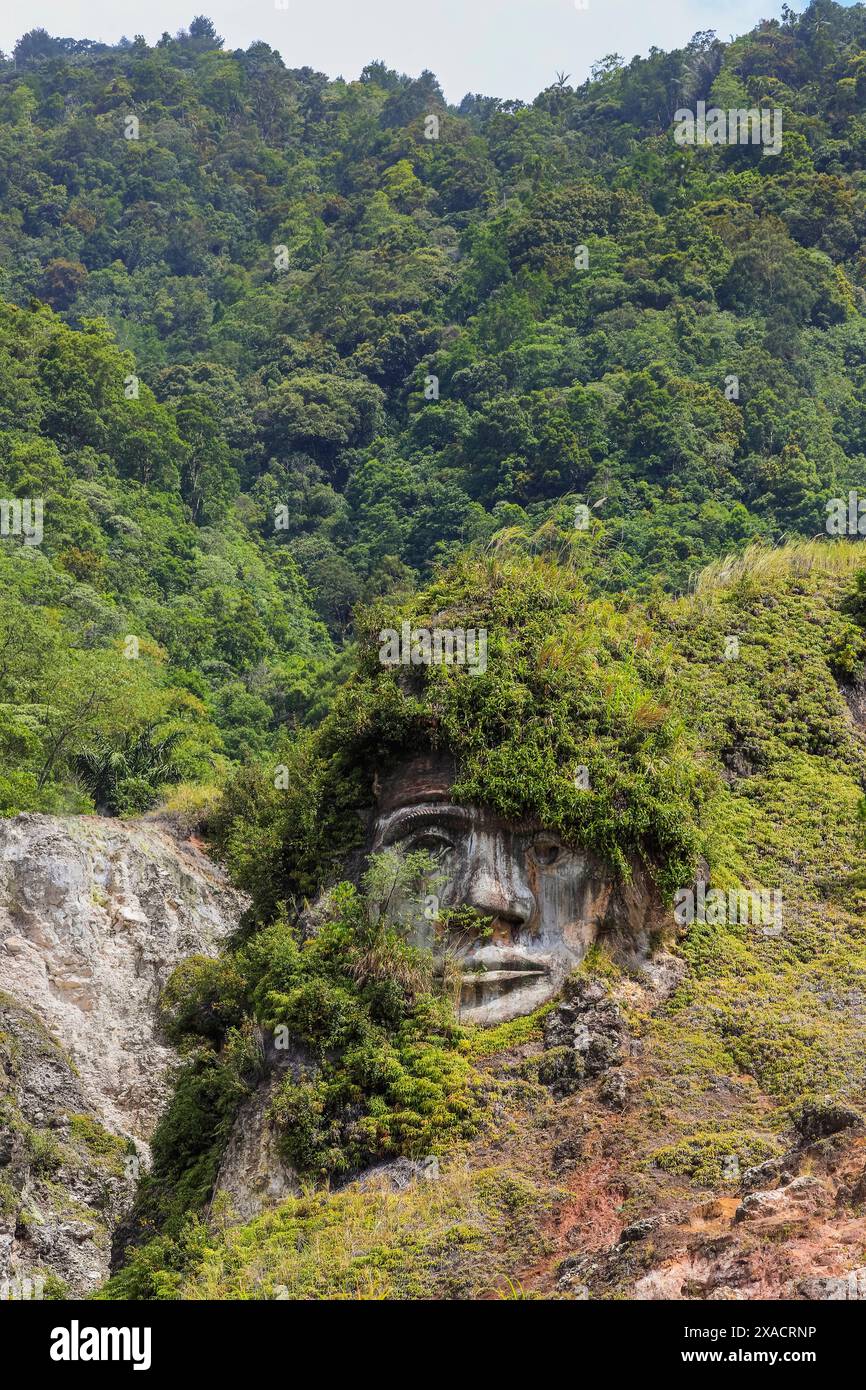 Großes, geschnitztes Gesicht in Bukit Kasih, einem vulkanischen Touristenpark mit Fumarole-Feldern, einem Weltfriedenturm und Gotteshäusern von fünf großen Religionen, Stockfoto