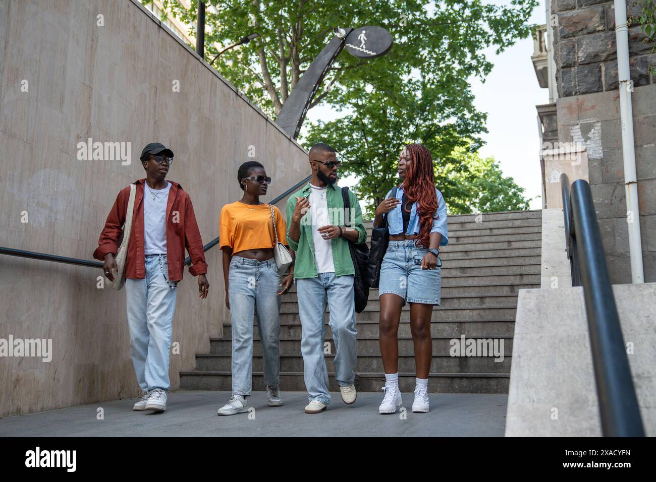 Eine Gruppe aufmerksamer afroamerikanischer Freunde diskutiert mit Begeisterung verschiedene Themen, spaziert im Freien Stockfoto