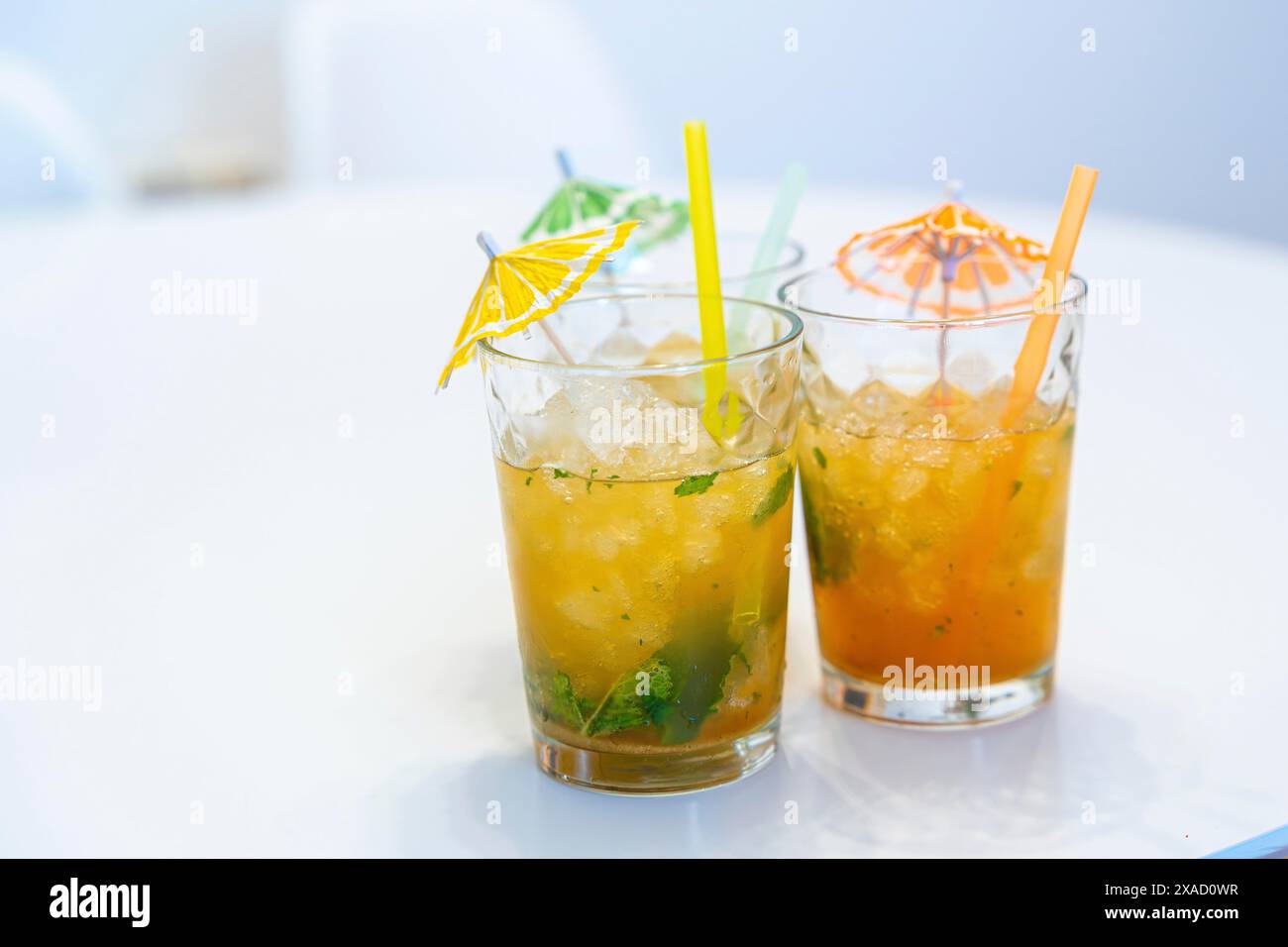 Drei Mojito-Cocktails mit Sonnenschirm und Strohhalm auf einem weißen Tisch Stockfoto