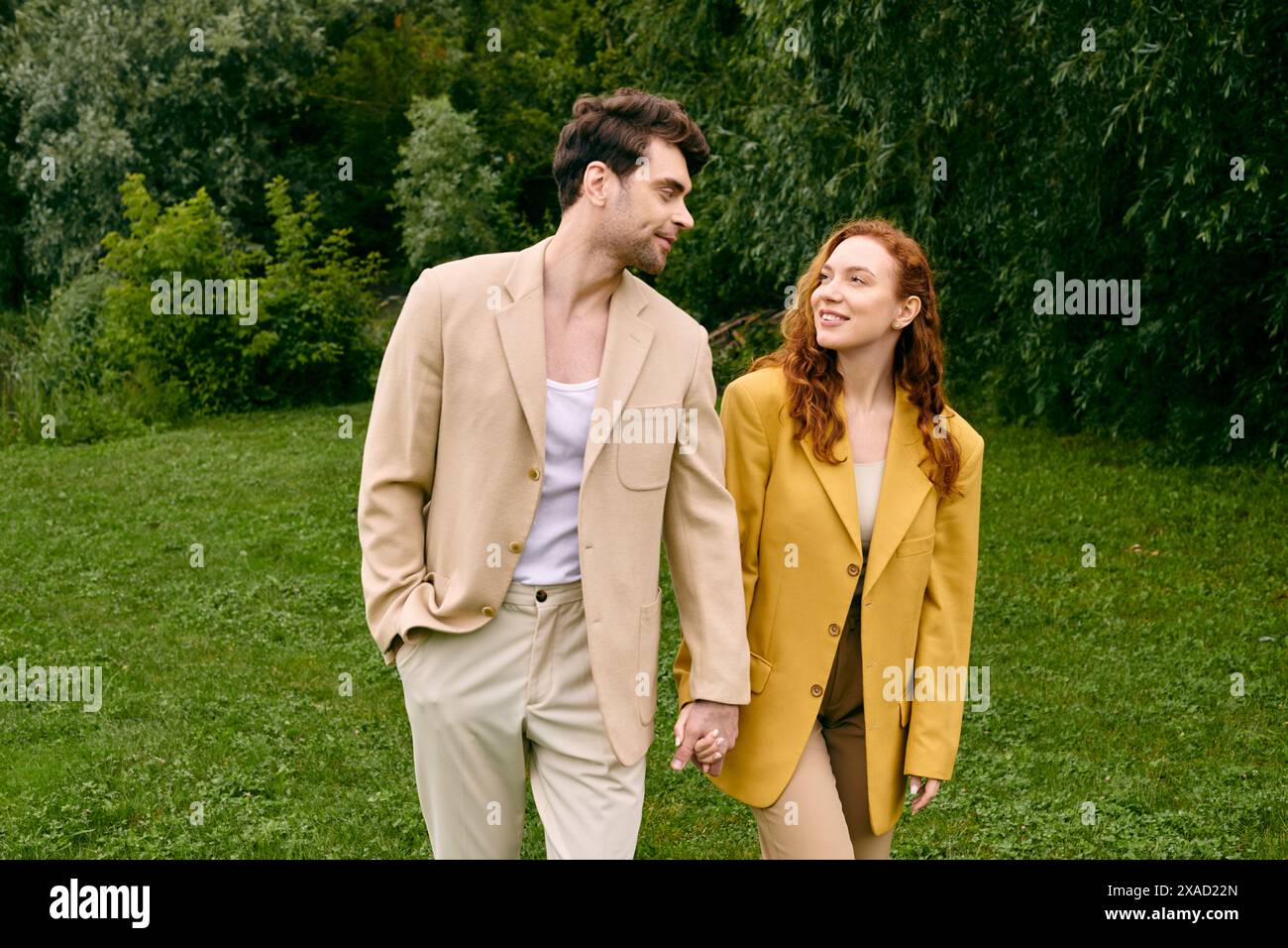 Ein Paar, das ein romantisches Date genießt, geht Hand in Hand durch ein üppiges grünes Feld, umgeben von Natur Schönheit. Stockfoto