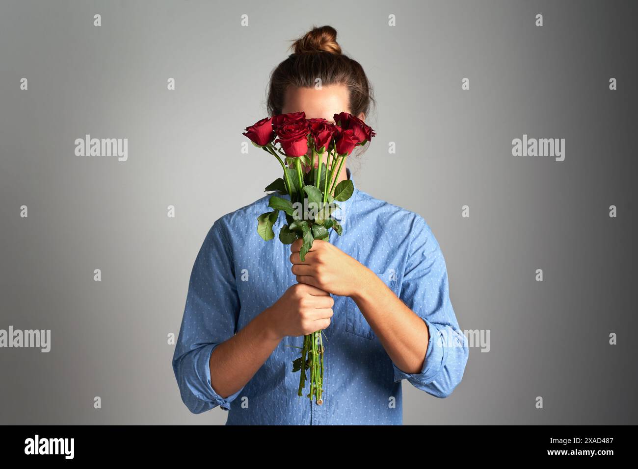 Rose, Geschenk und schüchterne Frau im Studio mit Blumenstrauß für Entschuldigung und Verständnis, Fehler und Vergebung auf grauem Hintergrund. Pflanzen, Verstecken und Stockfoto