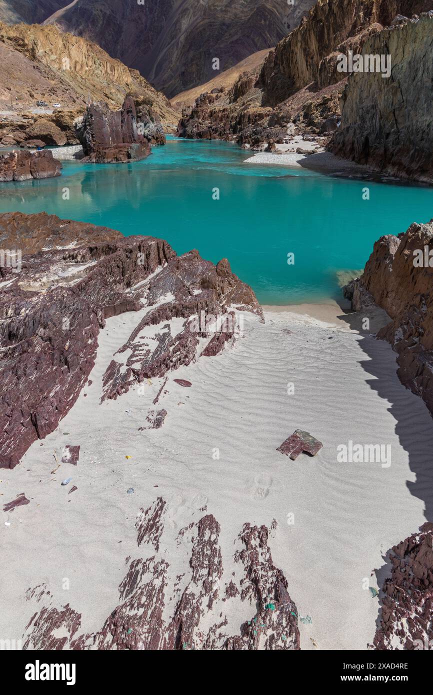 Landschaft mit Sandstränden inmitten zerklüfteter Bergfelsen und klarem, grünem Wasser in Ladakh. Stockfoto