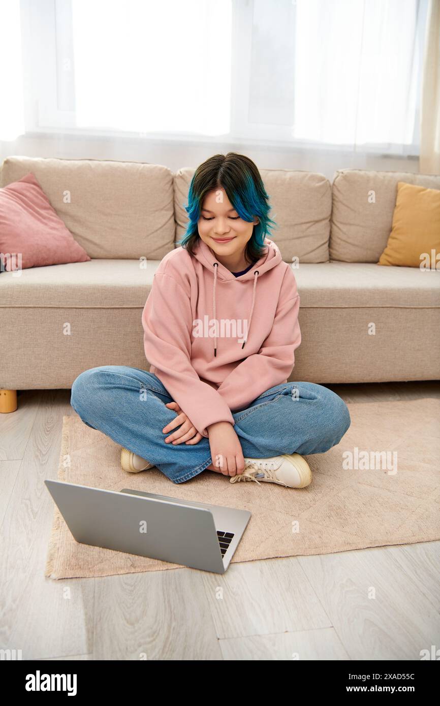 Ein asiatisches Teenager-Mädchen sitzt auf dem Boden, vertieft in Laptop Stockfoto