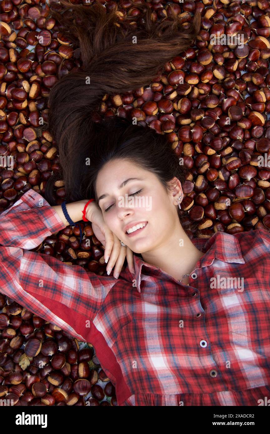 Schönes Modemodell in schottischem rotem Hemd, das auf Kastanienteppich liegt Stockfoto