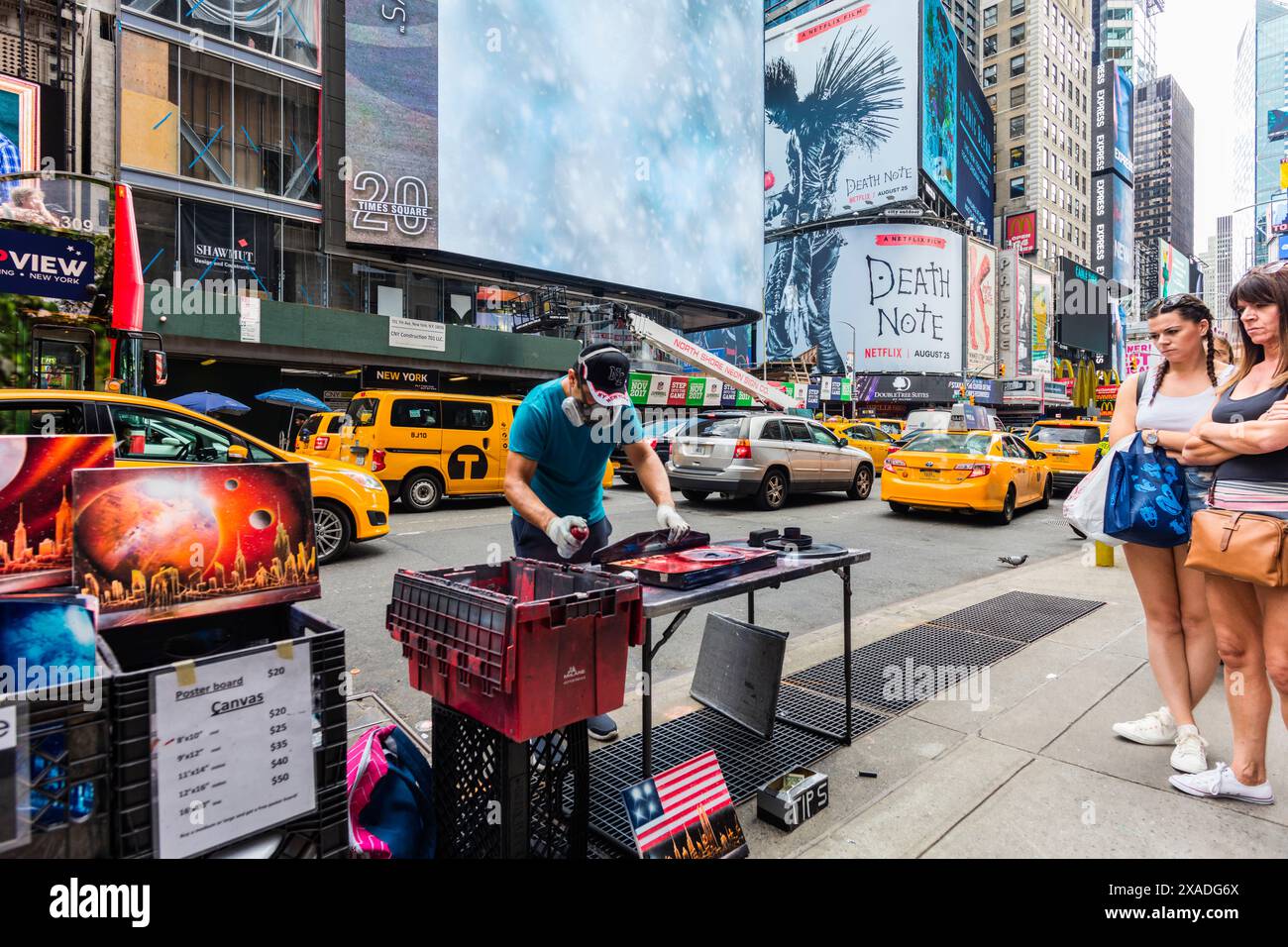 New York City, USA - 25. August 2017: Frauen beobachten einen Maler, der mit Sprühfarbe arbeitet, in der Nähe der Ecke 7th Avenue und West 47th Street. Stockfoto