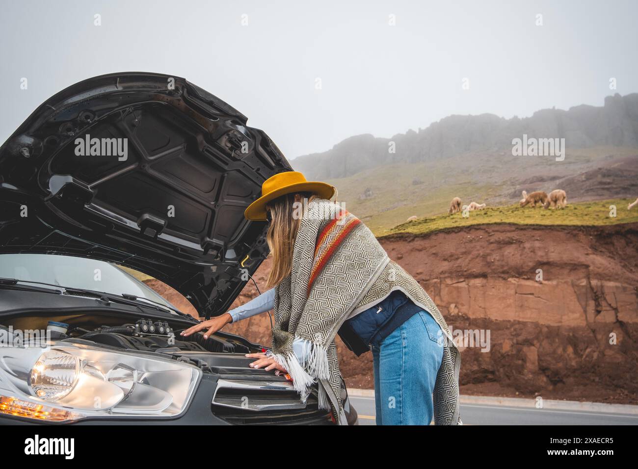 Eine Frau steht neben einem Auto mit gezogener Kapuze, Tourist in der peruanischen Andesmyla Stockfoto