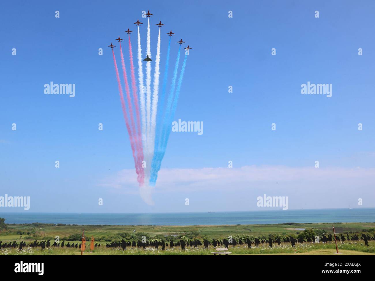 Die Roten Pfeile mit einem Taifun FGR4-Flugzeug, bemalt mit schwarz-weißen Streifen auf den Flügeln und dem Rumpf, auch bekannt als Invasionsstreifen oder D-Day-Streifen, damit Armee und Marine Freund von Feind unterscheiden können. führen Sie einen Überflug über die britische nationale Gedenkveranstaltung zum 80. Jahrestag des D-Day in Ver-sur-Mer, Normandie, Frankreich, durch. Bilddatum: Donnerstag, 6. Juni 2024. Stockfoto