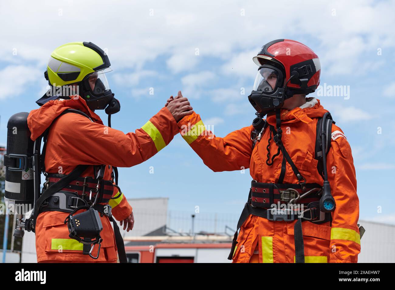 Ein vereintes Team von Feuerwehrleuten, die in ihren Uniformen verziert sind, feiert eine herzliche Feier, die von triumphalen Grußworten und Jubeln geprägt ist und die verkörpert Stockfoto