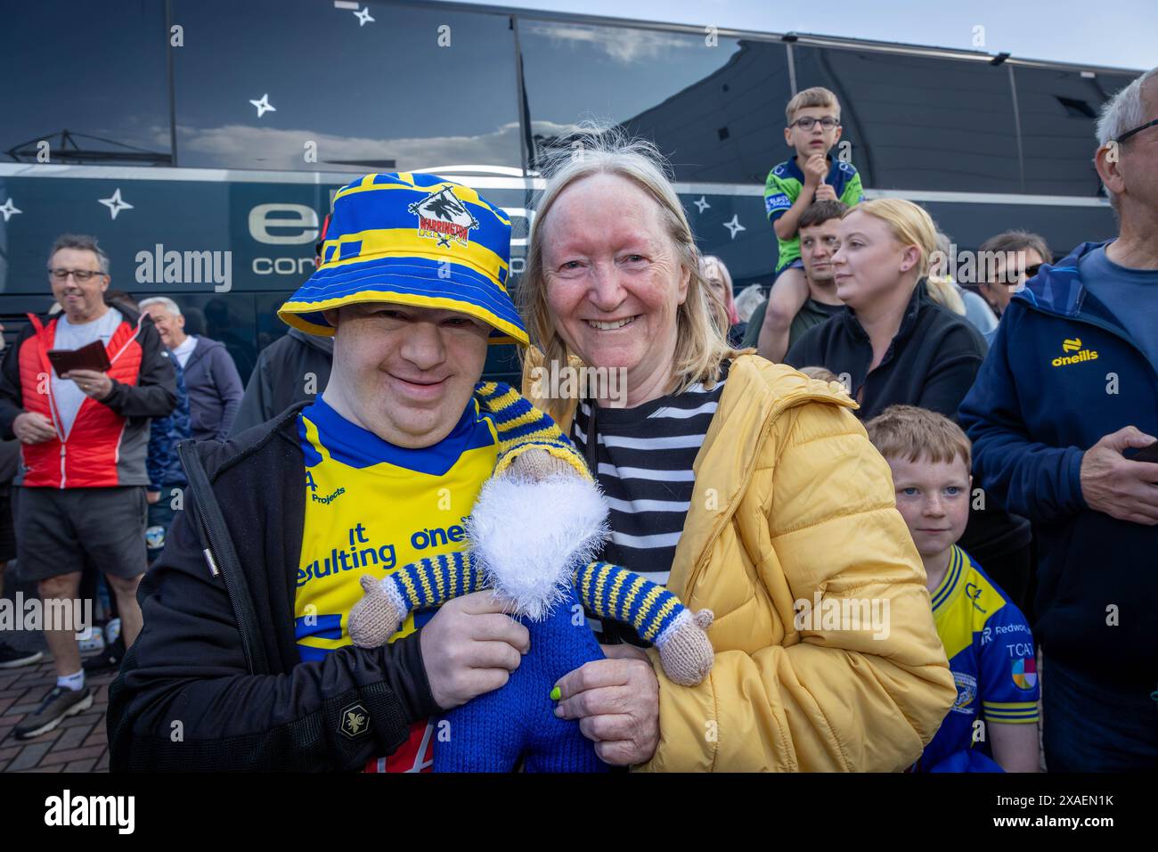 Warrington, Cheshire, Großbritannien. Juni 2024. Warrington Wolves verließ das Halliwell Jones Stadium am 6. Juni 2024 und zog in Richtung Wembley Stadium, um das Finale des Rugby Football League Challenge Cup gegen Wigan zu erreichen. Die Unterstützer waren da, um sie abzuhauen. Ein treuer Unterstützer mit Special Needs und seiner Mutter gab dem Team einen handgestrickten Warrington Wolves Gonk Credit: John Hopkins/Alamy Live News Stockfoto