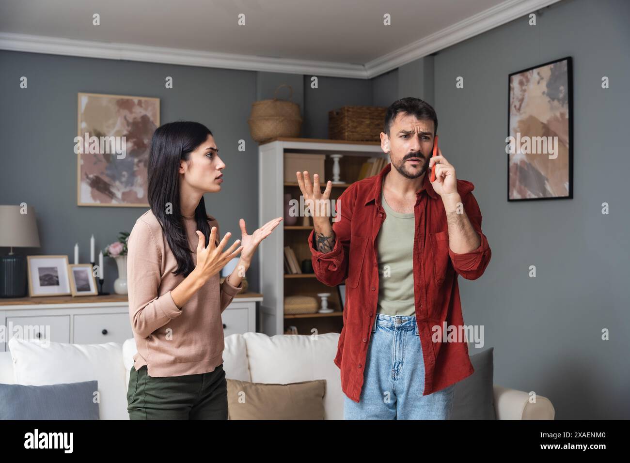 Ein junges Paar ruft die Polizei an, um häusliche Gewalt zu melden. Mann und Frau rufen 911 an, um laute Geräusche von der Wohnung oben zu melden, streiten und schreiende Stimmen. Stockfoto