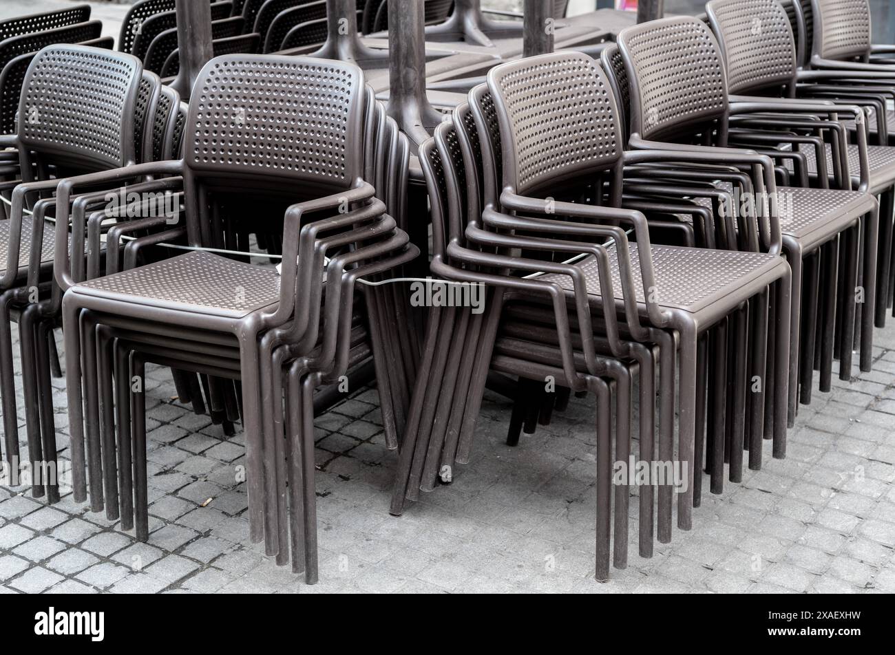 Graue Stühle eines Straßencafés werden an einem Ort gesammelt Stockfoto