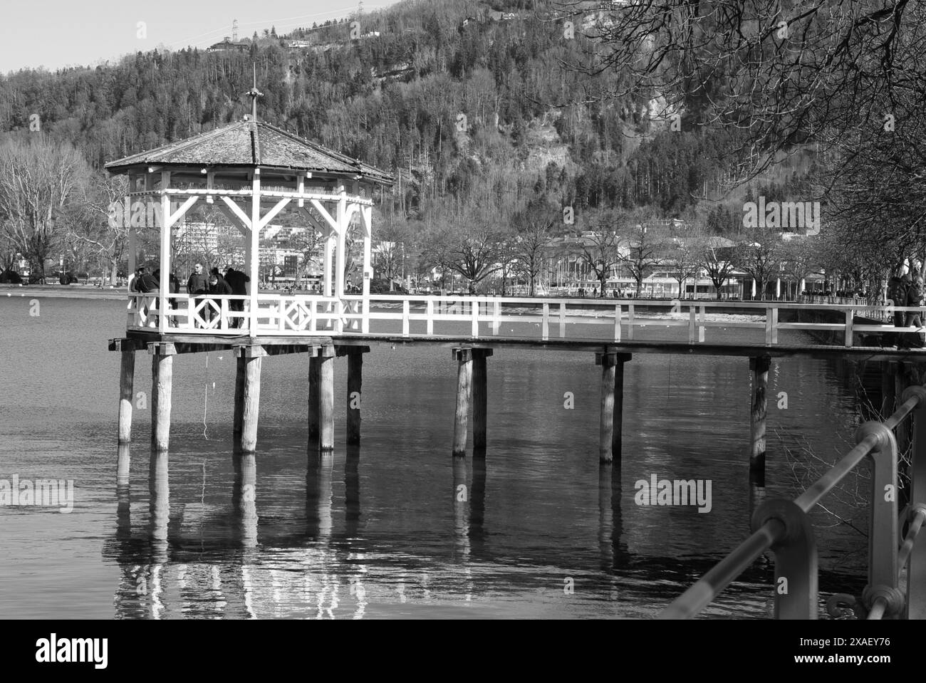 Ein Schwarzweißfoto eines Piers mit Pavillon und Brücke. Das Wasser ist ruhig und der Himmel ist klar Stockfoto