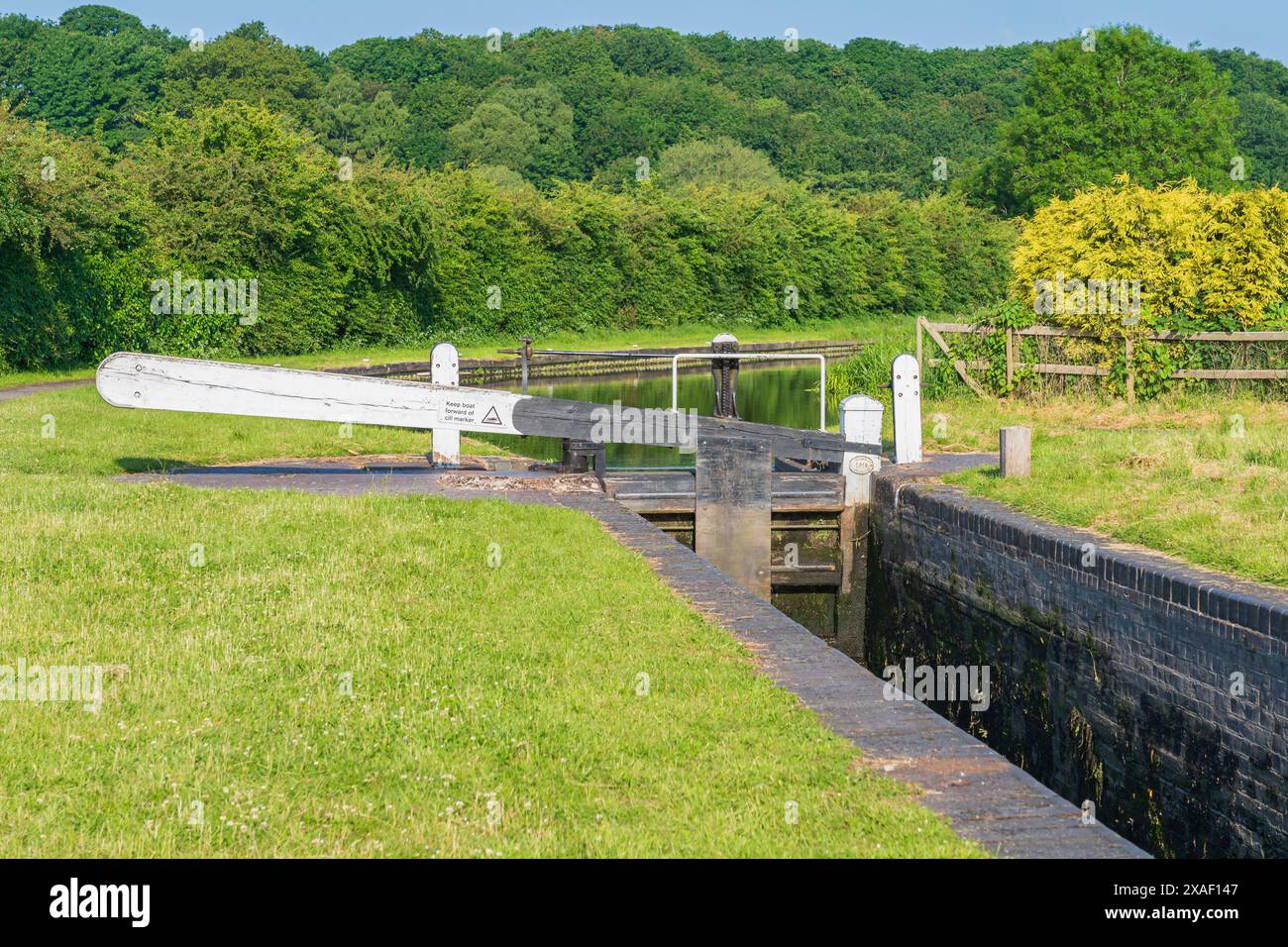 Boote oder Kanalkähne, die an einem Morgen mit blauem Himmel an der Seite des Kanals in Großbritannien verankert sind Stockfoto