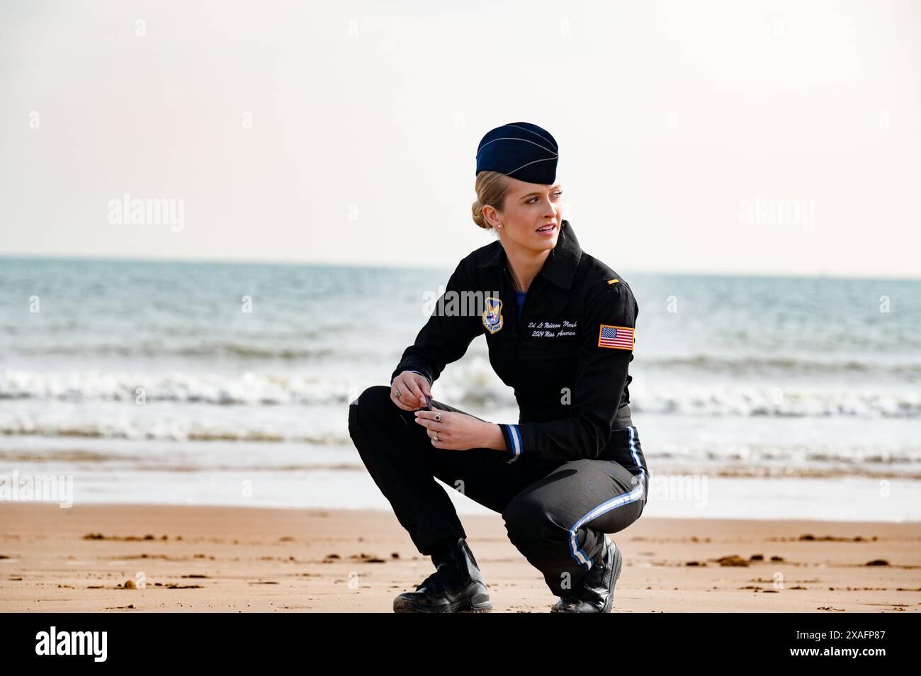 Vierville-sur-Mer, Frankreich. Juni 2024. U. S Air Force 2nd Lieutenant Madison Marsh, gekrönt Miss America 2024, kniet während der Dreharbeiten an Omaha Beach nieder, in dem die Bedeutung der Vermächtnis des D-Day am 3. Juni 2024 in Vierville-sur-Mer, Normandie, erklärt wird. Frankreich. Marsh, ein 22-jähriger Absolvent der U.S. Air Force Academy, ist der erste Militäroffizier im aktiven Dienst, der die Krone als Miss America trägt. Kredit: Miriam Thurber/U. S Air Force Photo/Alamy Live News Stockfoto