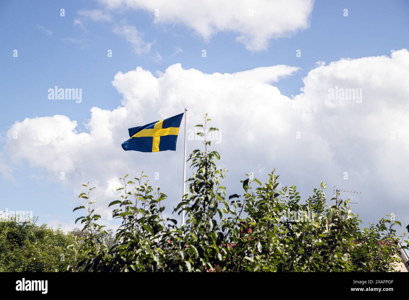 Die schwedische Flagge fliegt mit weißen Wolken gegen den blauen Himmel Stockfoto