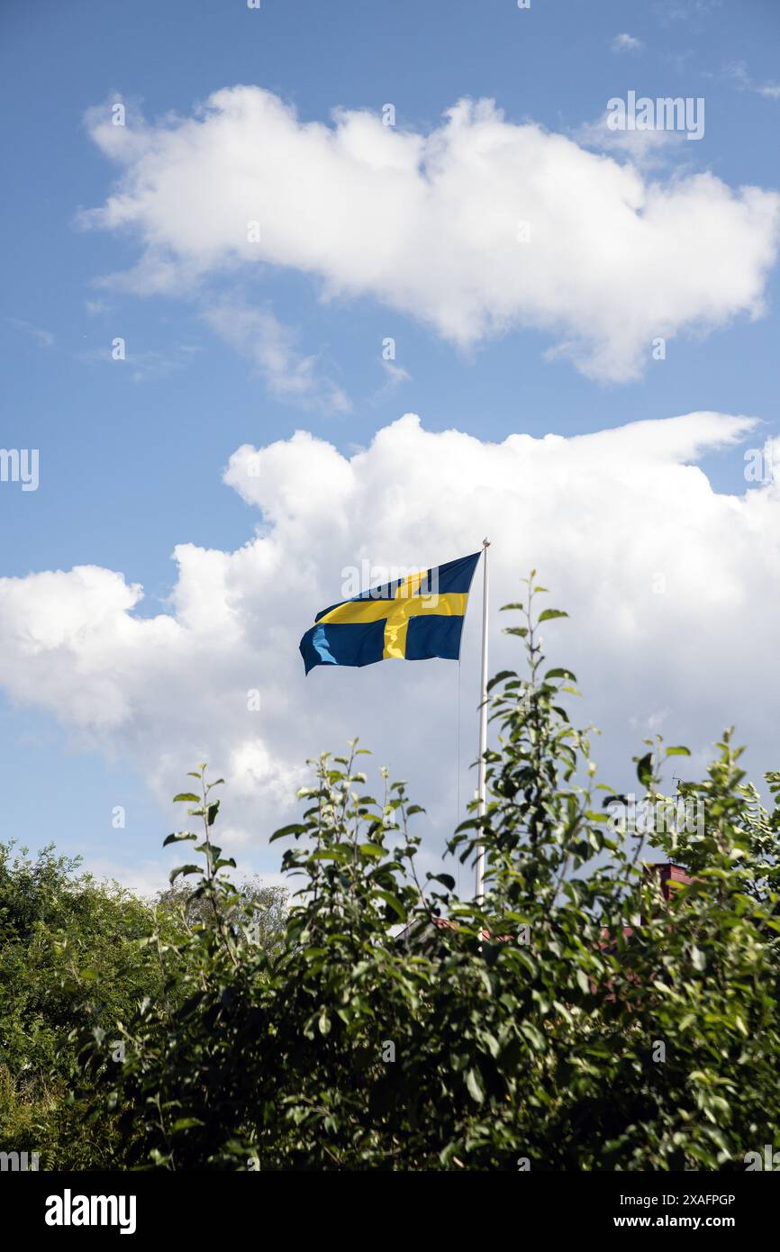 Die schwedische Flagge fliegt mit weißen Wolken gegen den blauen Himmel Stockfoto