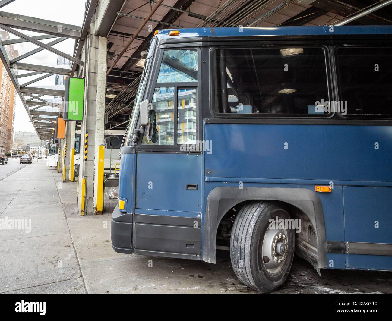 Ein Fernbus parkt und ist bereit für die Abfahrt an einem stark frequentierten Busbahnhof in Nordamerika. Das Bild fängt das Wesen des öffentlichen Verkehrs ein Stockfoto