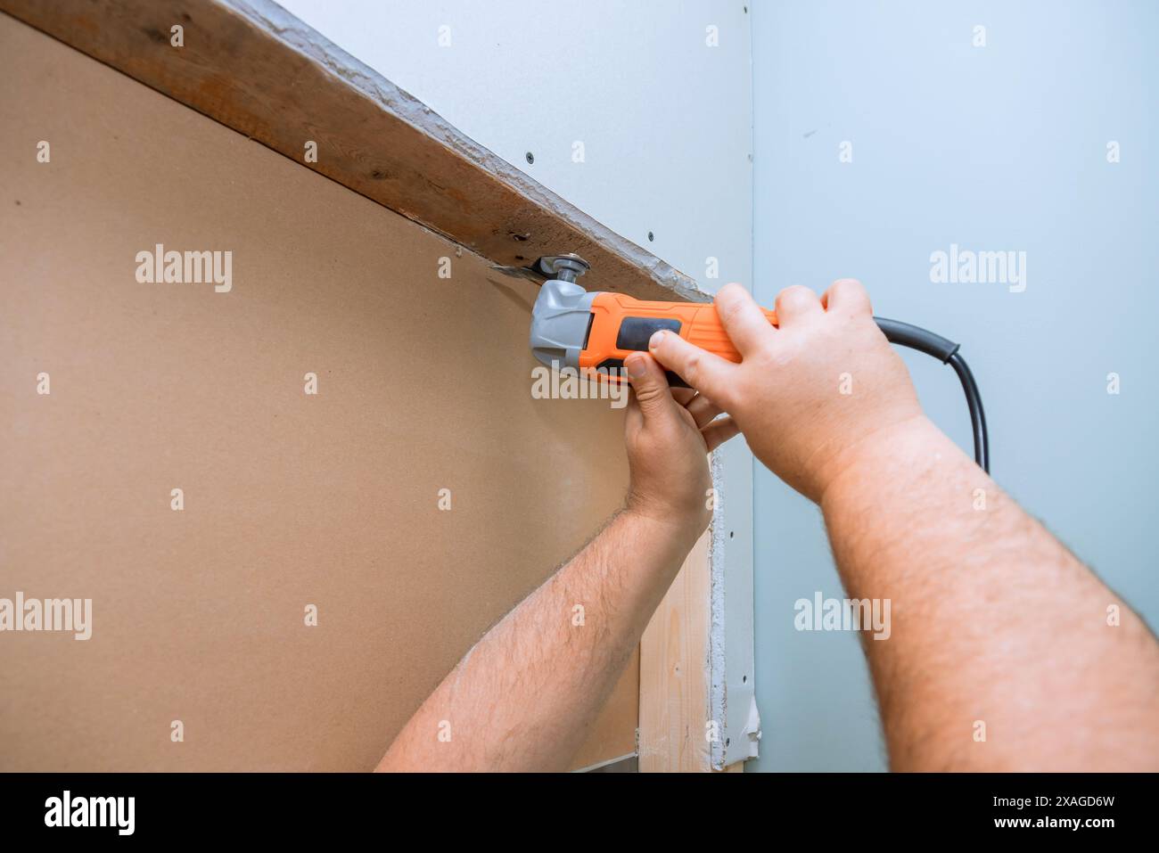 Ein Mitarbeiter schneidet Trockenbauteile mit mehreren Werkzeugen in der Wand Stockfoto